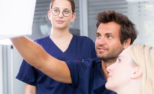 Zwei Oralchirurgen informieren Patientin über die Behandlung